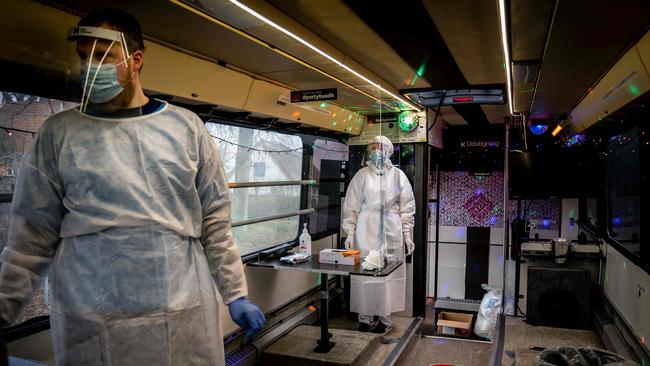 Medical staff carry out a COVID-19 PCR tests in a “Partybus” with music and disco lights converted into a mobil lab in Ishoj, Denmark. Picture: AFP