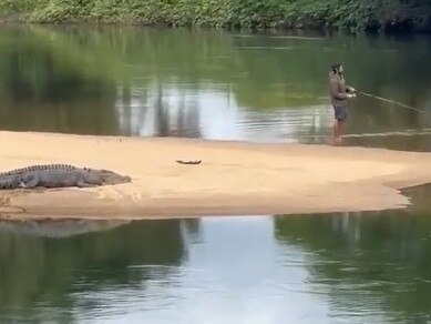 ‘D**khead’ caught on video fishing metres from huge croc