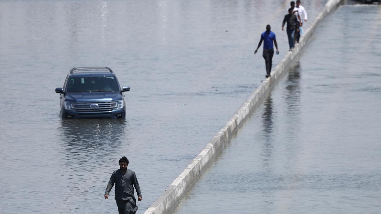 People walk along an flooded highway on April 18 in Dubai. Picture: Francois Nel/Getty Images