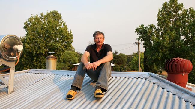 Andrew Jackson sits on the roof of his home where he stayed the night when the fire front passed through. Picture: Aaron Francis