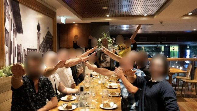 Tom Sewell, holds a photo of Adolf Hitler at The Hof Downtown Bavarian beer hall in the Docklands, while junior members of his racist group perform Nazi salutes.