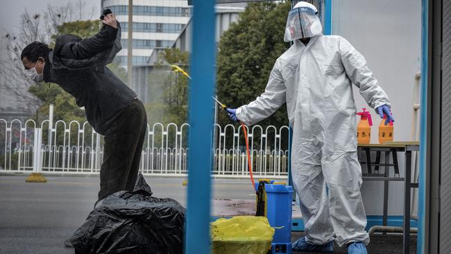 This photo taken on February 22, 2020 shows a man who has recovered from the Covid-19 coronavirus infection being disinfected by a medical staff before leaving the hospital in Wuhan in China. Picture: AFP