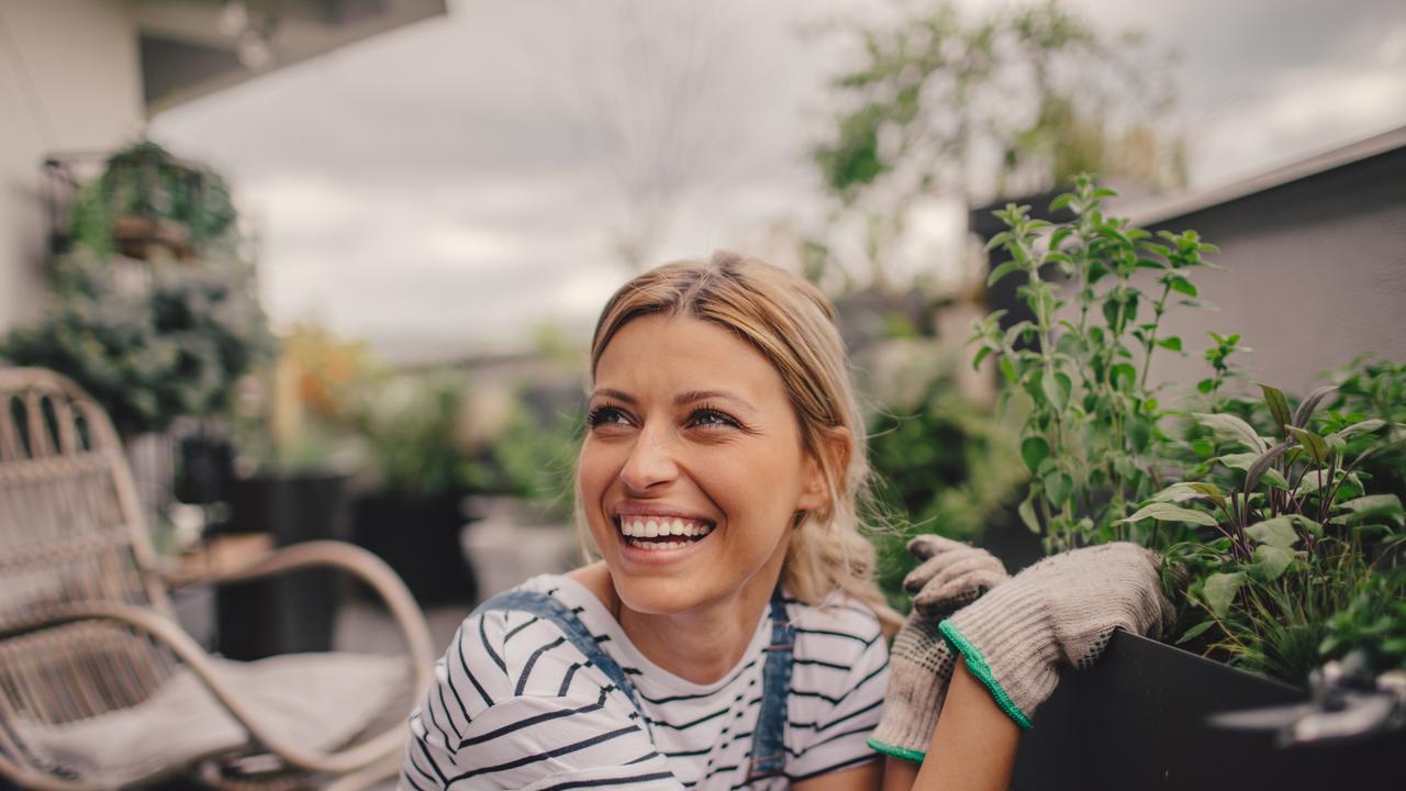 Young woman arranging plants in her rooftop garden; generic gardening