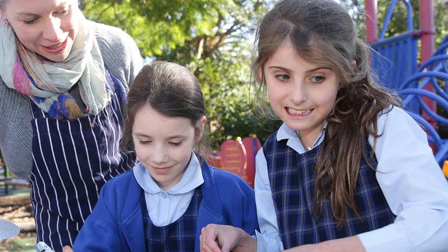 Year 3 students Sarah Zeppel and Isabel Johnston prepare Asian rice paper rolls with teacher Beth Dowdle.