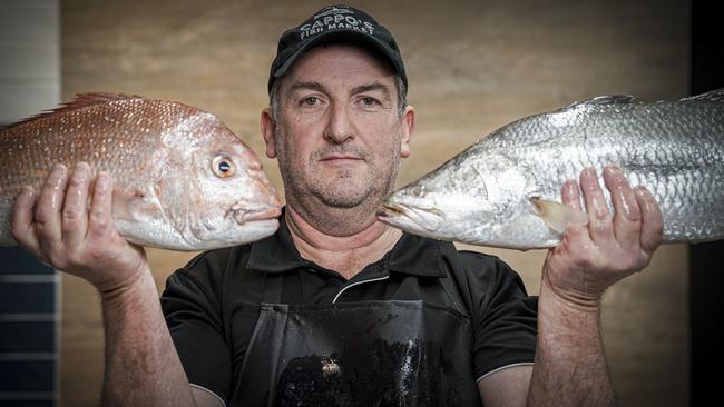 Matt Cappo from Cappo’s Seafood in the Adelaide Central Market with a locally caught Snapper and a Northern Territory barramundi. Picture: AAP / Mike Burton