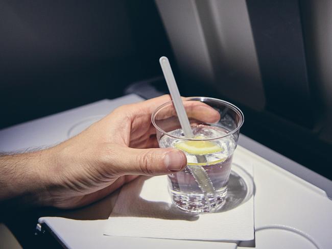 Traveling by airplane. Passenger enjoying gin and tonic drink in economy class during flight. Picture: istock