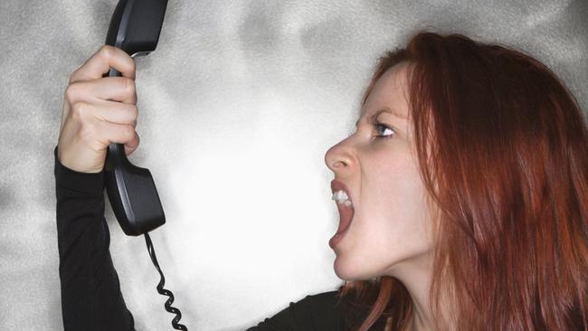 Generic photo of a woman screaming into telephone. Rage. Angry.