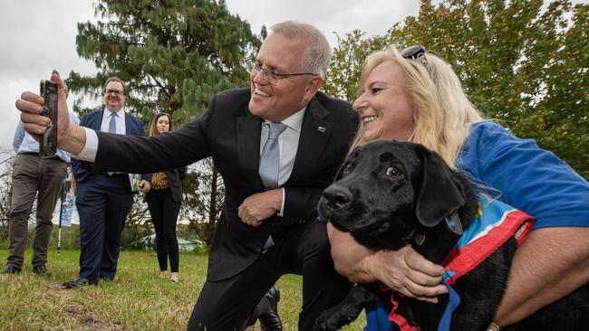 Scott Morrison tries to pose with a decidedly unsure assistance dog in the battleground western Sydney electorate of Lindsay on Tuesday. Picture: Jason Edwards