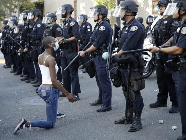 A masked protester kneels before San Jose police. Picture: AP