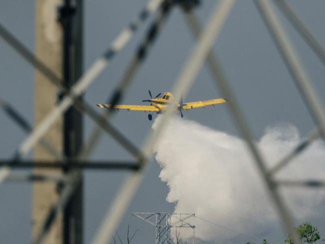 Firefighting aircraft and Firefighters defend Power infrastructure from an out of control fire in Berrimah. Picture: Glenn Campbell Picture: Glenn Campbell