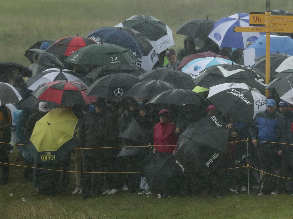 Spectators use umbrellas to shelter from the driving rain. (AP Photo/Jon Super)