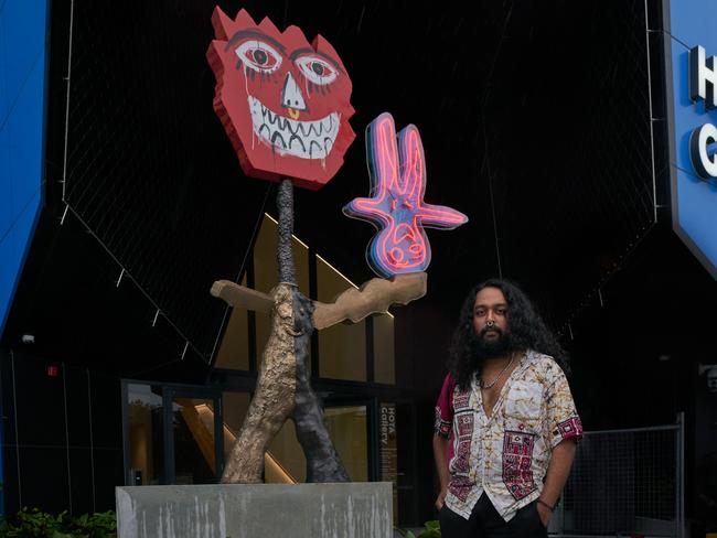 Artist Ramesh Mario Nithiyendran with his new sculpture at the entrance to the HOTA Gallery. Photo: Alex Chomciz.