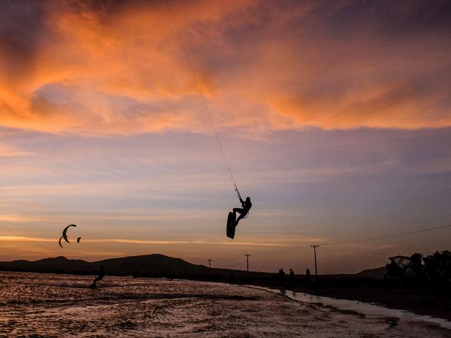 Amateur and professional kitesurfers are pictured in Cabo de la Vela, Guajira Department, Colombia, on July 4, 2016. In Cabo de la Vela, a remote destination in the extreme northeast of Colombia, members of the Wayuu indigenous tribe seek to tame the art of kitesurfing, a sport that has become a source of income in this impoverished region of the Caribbean as well as the challenge of competition. / AFP PHOTO / Joaquin Sarmiento