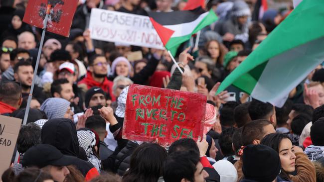 Pro-Palestine rally, including a sign that reads ‘From the River to the Sea’ chant slogans under Palestinian flags during a ’Freedom for Palestine’ protest.