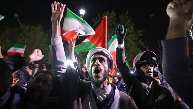 Demonstrators wave Iran's flag and Palestinian flags as they gather in front of the British Embassy in Tehran.