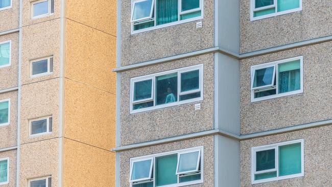 A resident living in the Flemington Public housing tower is seen looking out the window during last month’s lockdown. Picture: Getty Images