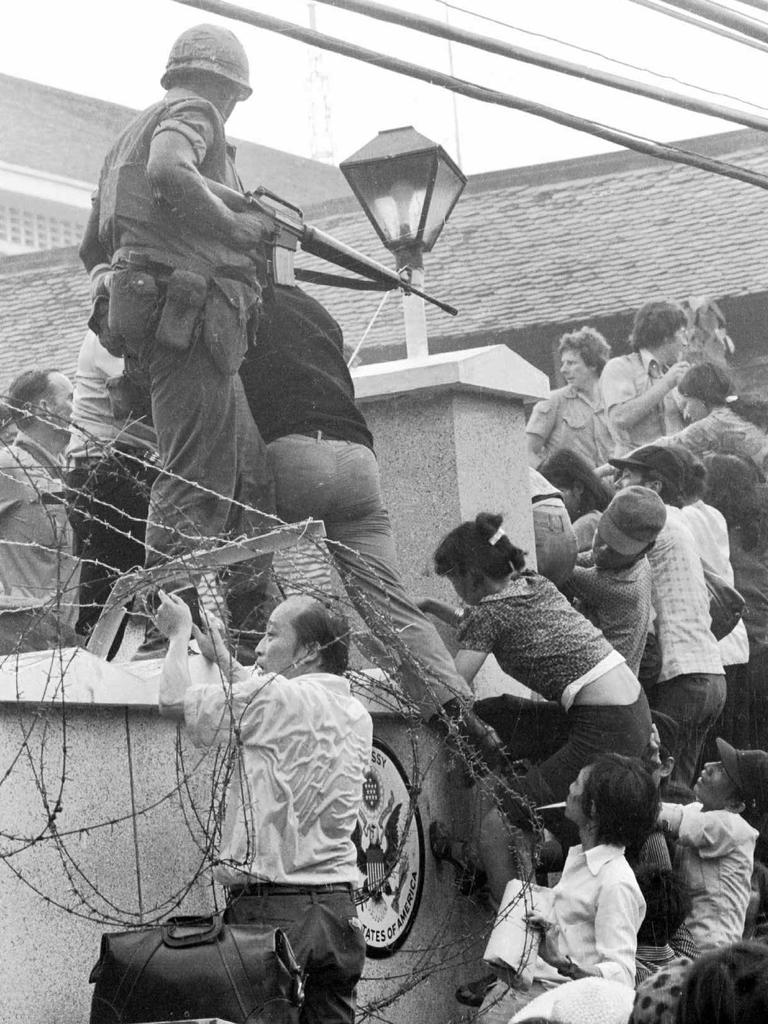 People scaling the wall of the US Embassy in Saigon, trying to reach evacuation helicopters, in April 1975. Picture: AP Photo/Neal Ulevich