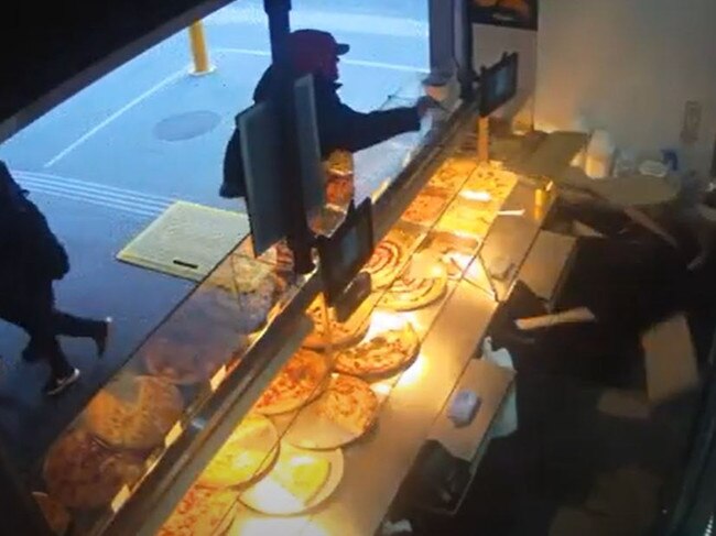 A man pushes items off the bain marie in anger at a fast food business in Elizabeth Street.