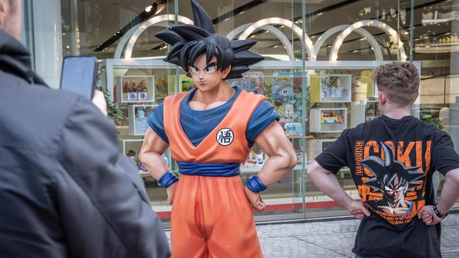 A tourist wearing a T-shirt of <i>Dragon Ball</i> has his photographs taken with a statue of <i>Dragon Ball</i> character Son Goku in Tokyo on March 8, 2024. Picture: AFP