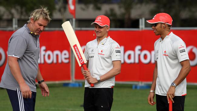 Hamilton and teammate Heikki Kovalainen get cricket lessons from the legendary Warnie.