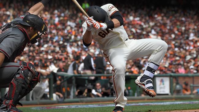 Buster Posey #28 of the San Francisco Giants falls backwards after he was hit in the head with a pitch.