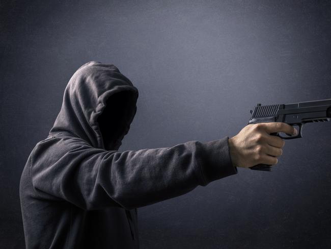 Hooded man with a gun in the dark istock image