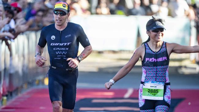 Cairns Iron Man - 3rd Place Pro Winner  Sam Appleton about to finish with right  local Asako Blain from Bentley Park takes the crowds applause. Picture: Brian Cassey