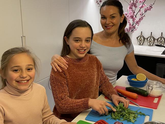 Patricia Cencigh with daughters Charlize, 13 (centre) and Alegra, 10 cooking together while locked down at home in Enmore, Sydney.