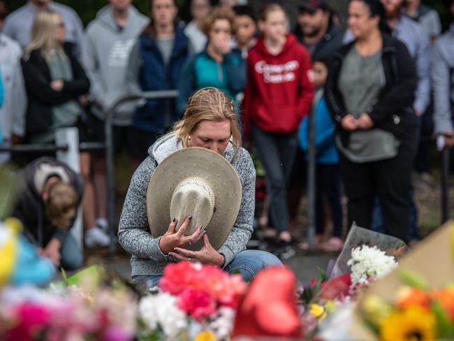 CHRISTCHURCH, NEW ZEALAND - MARCH 17: A woman holds her hat to her face as she pauses next to flowers laid near Al Noor mosque on March 17, 2019 in Christchurch, New Zealand. 50 people are confirmed dead, with 36 injured still in hospital following shooting attacks on two mosques in Christchurch on Friday, 15 March. 41 of the victims were killed at Al Noor mosque on Deans Avenue and seven died at Linwood mosque. Another victim died later in Christchurch hospital. A 28-year-old Australian-born man, Brenton Tarrant, appeared in Christchurch District Court on Saturday charged with murder. The attack is the worst mass shooting in New Zealand's history. (Photo by Carl Court/Getty Images)