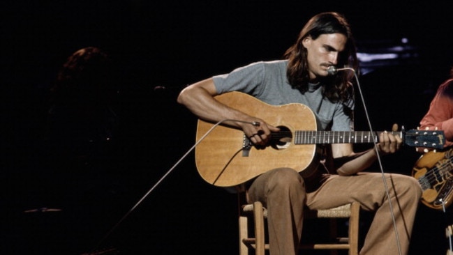 James Taylor playing the guitar while sitting on a chair during a concert, circa 1970. Picture: David Warner Ellis/Redferns/Getty Images