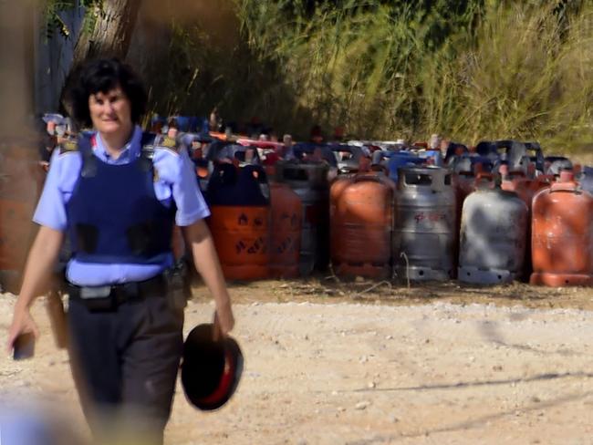 A policewoman walks with dozen of gas bottles in background in Alcanar during a search linked to the Barcelona and Cambrils attacks on the site of an explosion. Picture: AFP