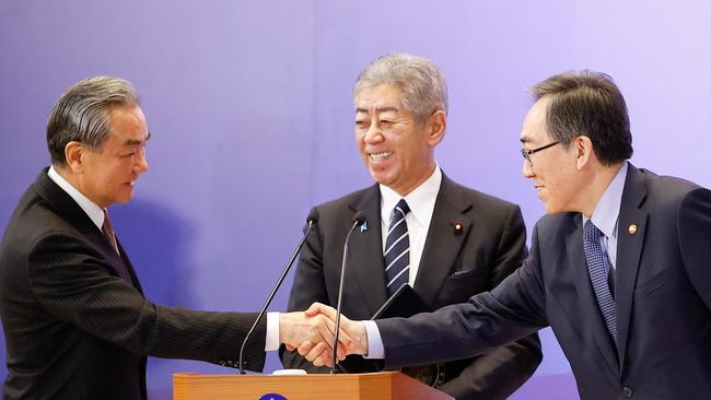 China's Foreign Minister Wang Yi (left) and South Korea's Foreign Minister Cho Tae-yul shake hands as Japan's Foreign Minister Takeshi Iwaya looks on. Picture: Rodrigo Reyes Marin / POOL / AFP