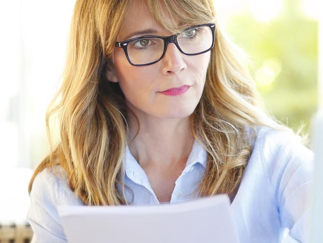 Portrait of confident businesswoman doing some paperwork and using laptop while working at coffee shop.