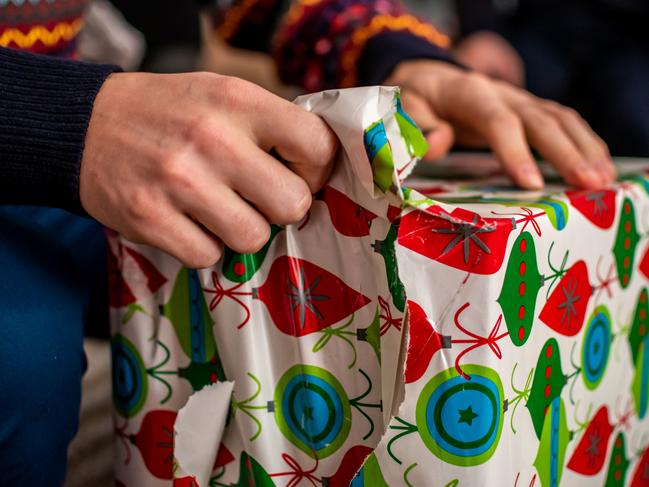 Young man opening a Christmas present during a family gathering.