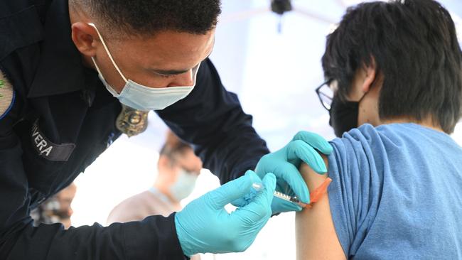 Brandon Rivera, a Los Angeles County emergency medical technician, gives a second does of Pfizer-BioNTech Covid-19 vaccine to Aaron Delgado, 16. Picture: AFP