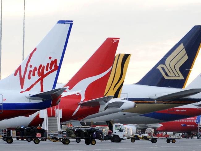 Passenger aircraft heading for fog bound Melbourne were diverted to Adelaide Airport. Vertical stabilisers of Qantas, Virgin, Tiger, Singapore Airlines and Malaysia Airlines aeroplanes waiting on tarmac at airport.