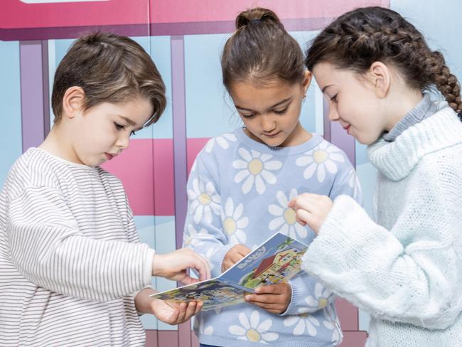 Vincent Santos, 5, Ella Seale, 7, and Sibella Evans, 7, are looking at a new a special new collection of Bluey Dollarbuck coins. Picture: Scott Ehler