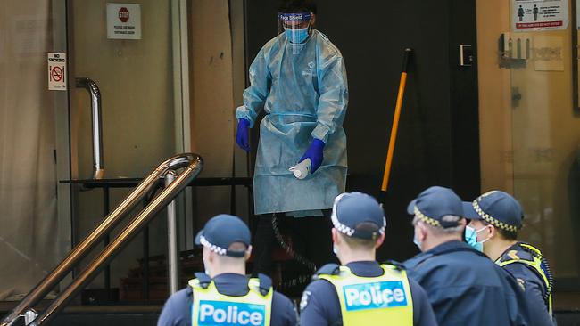 A man decontaminates the steps of a quarantine hotel on August 11 after a young woman who walked out was taken away by paramedics. Picture: Ian Currie