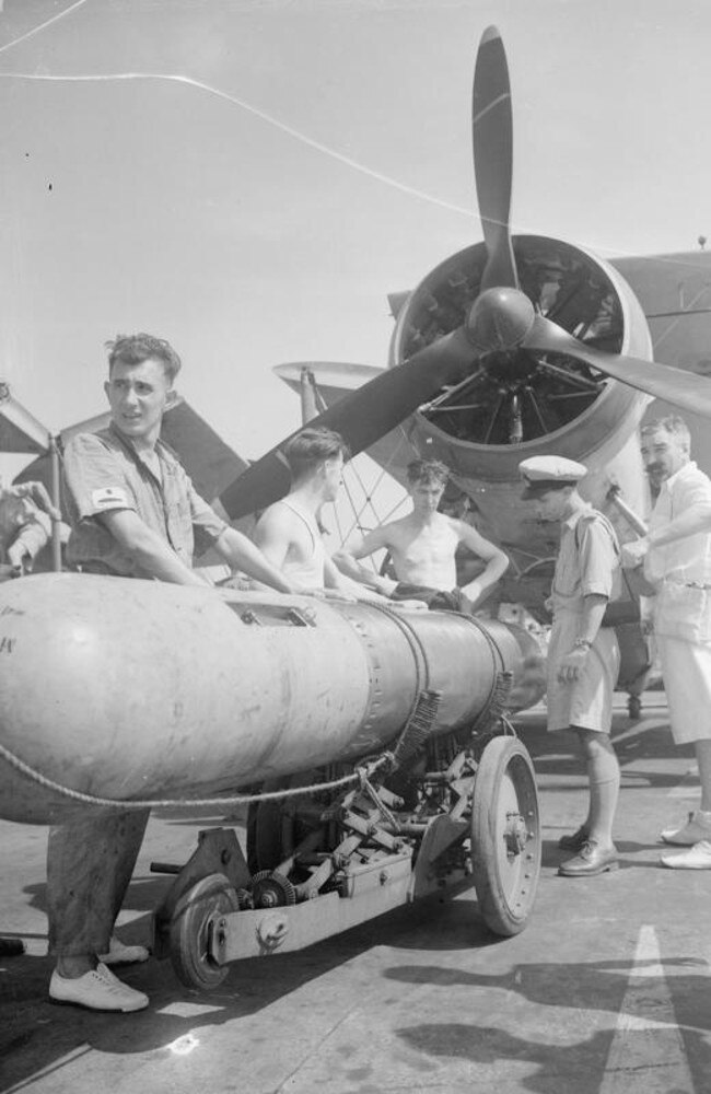 HMS Illustrious’ deck crews load a torpedo aboard a Swordfish biplane. Picture: IWM