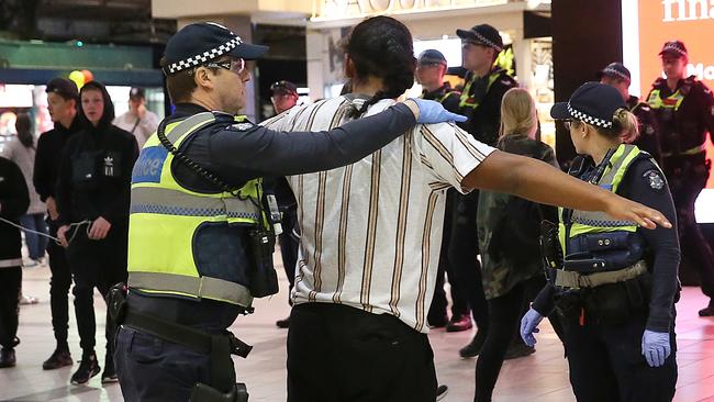 Police officers pat down a person at Flinders St train station. Picture: Ian Currie