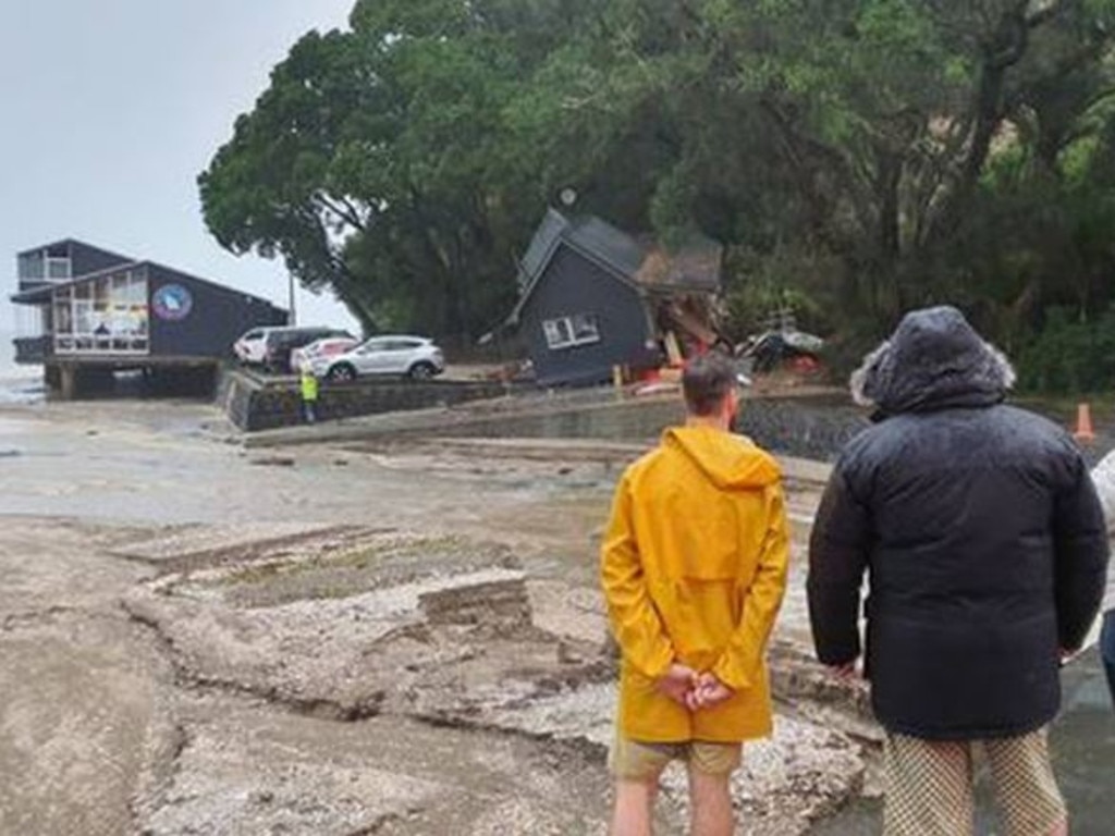 Residents at French Bay in west Auckland watch on after a slip damaged the Coastguard building. Photo / Meg Liptrot