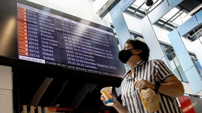 A woman walk past an arrivals board at Melbourne Airport displaying cancelled flights from Sydney. Picture: NCA NewsWire / David Geraghty