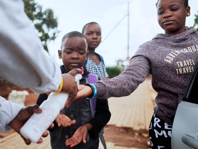 An International Red Cross member gives hand sanitiser to children in the Protea informal settlement in Soweto amid the coronavirus pandemic. Picture: Luca Sola/AFP