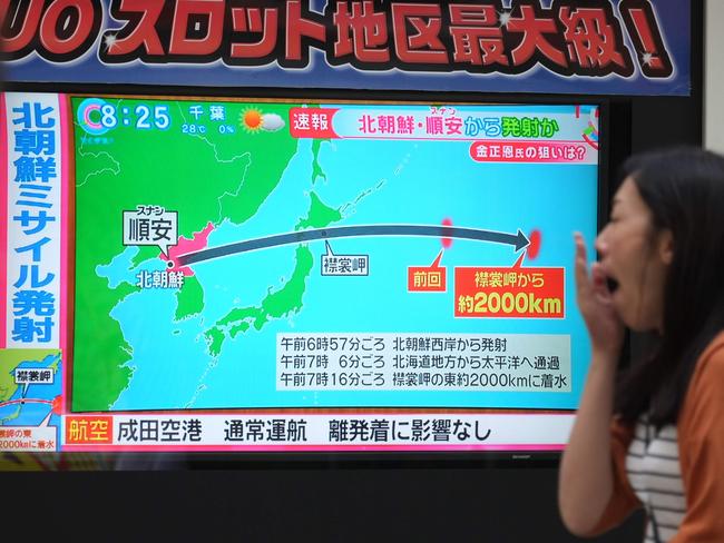 Pedestrians look at a television screen broadcasting a news report in Tokyo today following a North Korean missile test that passed over Japan. Picture: AFP
