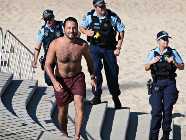 The swimmer was escorted off the sand by police after Coogee beach was closed. Picture: Adam Yip