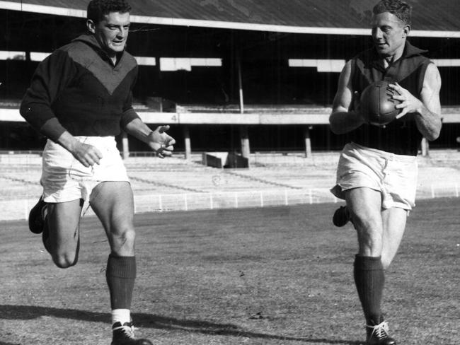 1964 premiership teammates Brian Dixon (left) and Bluey Adams sharpen up their handball at training.