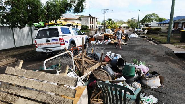 A woman walks past debris on Water Street, Bundaberg, after catastrophic flooding in January, 2013. At the time, about 1200 people remained in official evacuation centres, with 2000 homes affected by flooding as a result of ex-tropical cyclone Oswald.