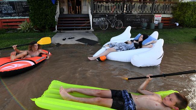 Pub worker Tahlia Thomasson (right) and local children play in floodwaters outside the Fitzroy Hotel in Rockhampton. Picture: AAP.