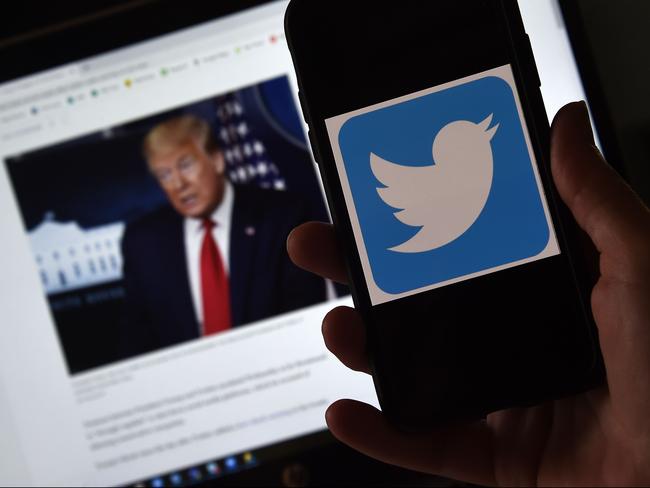 In this photo illustration, a Twitter logo is displayed on a mobile phone with a President Trump's picture shown in the background on May 27, 2020, in Arlington, Virginia. - US President Donald Trump threatened Wednesday to shutter social media platforms after Twitter for the first time acted against his false tweets, prompting the enraged Republican to double down on unsubstantiated claims and conspiracy theories. Twitter tagged two of Trump's tweets in which he claimed that more mail-in voting would lead to what he called a "Rigged Election" this November. (Photo by Olivier DOULIERY / AFP)