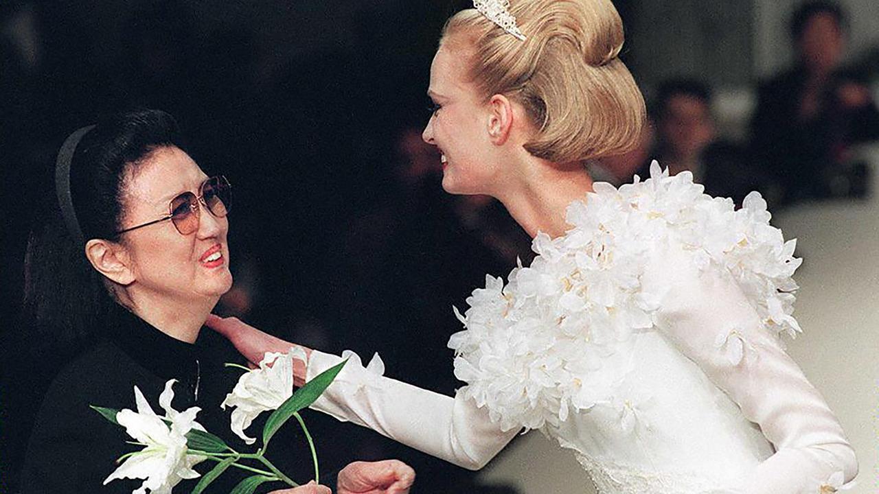 Japanese designer Hanae Mori receiving a lily from the model displaying her wedding dress in Paris. (Photo by PIERRE VERDY / AFP)